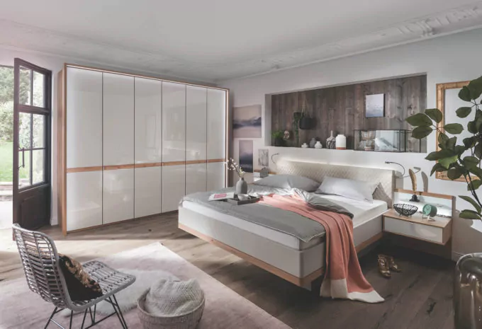 Schlafzimmer mit Doppelbett in Holzoptik und Kleiderschrank mit champagnerfarbigen Glastüren
